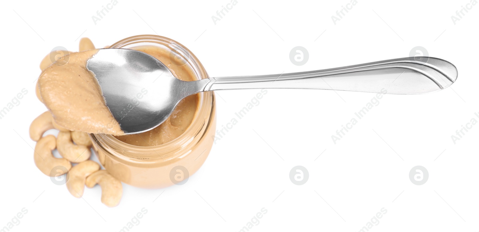 Photo of Tasty nut paste in jar, spoon and cashews isolated on white, above view