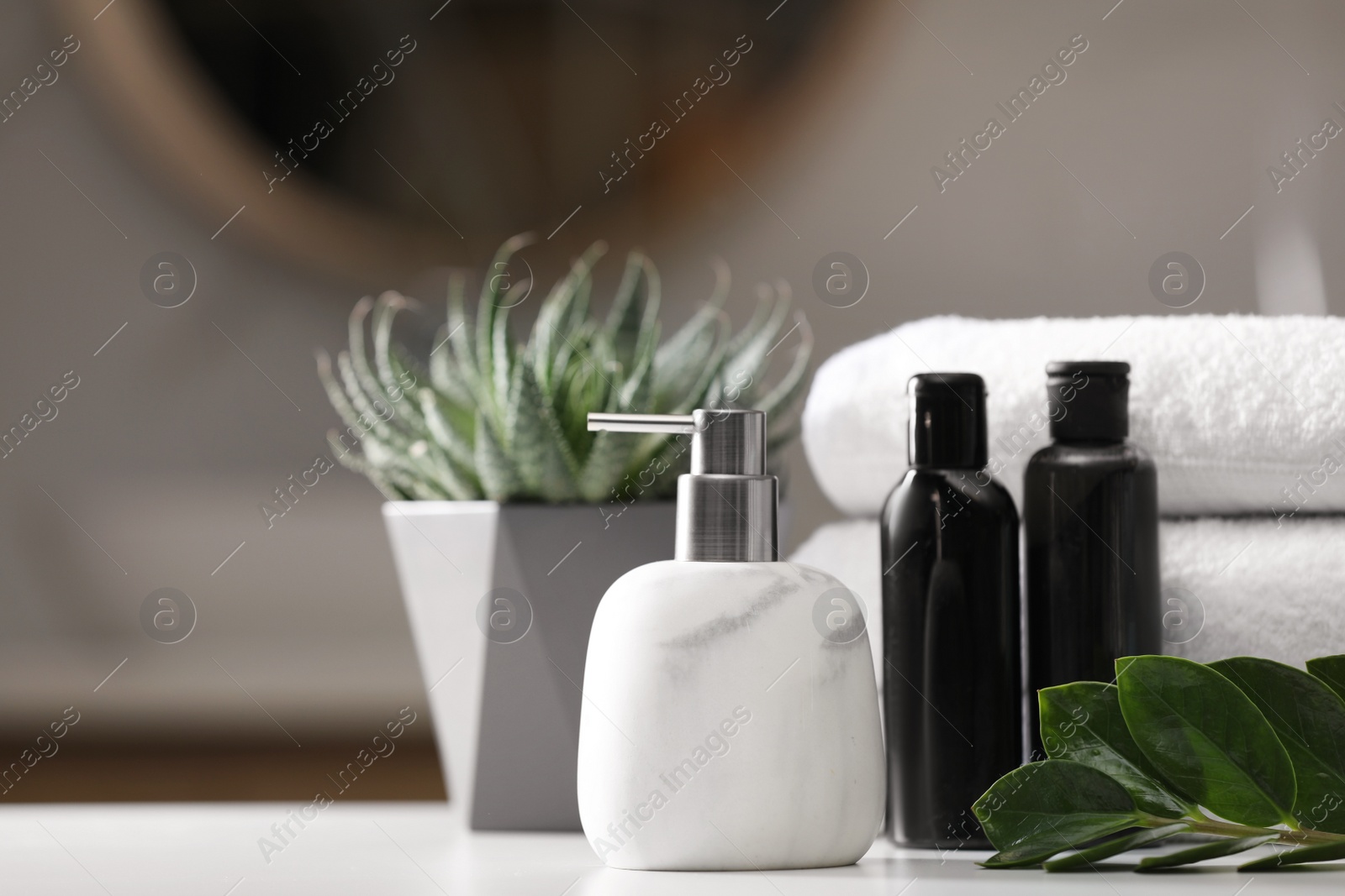 Photo of Composition with soap dispenser and towels on white table indoors. Space for text