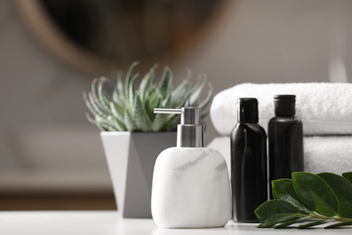 Composition with soap dispenser and towels on white table indoors. Space for text