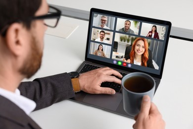 Image of Man having video chat with coworkers via laptop at white table, closeup