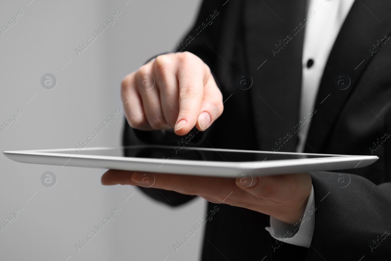 Photo of Closeup view of woman using modern tablet on grey background