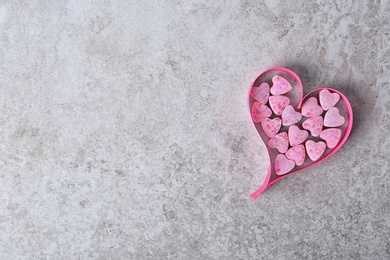 Small heart shaped candies with ribbon and space for text on gray background, top view