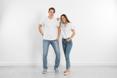 Young couple in stylish jeans near white wall