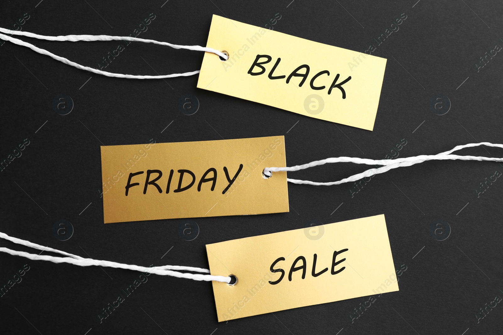 Photo of Blank golden tags on dark background, flat lay. Black Friday concept