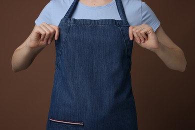 Photo of Woman wearing kitchen apron on brown background, closeup. Mockup for design