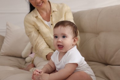Photo of Mother with her cute baby on sofa at home, closeup