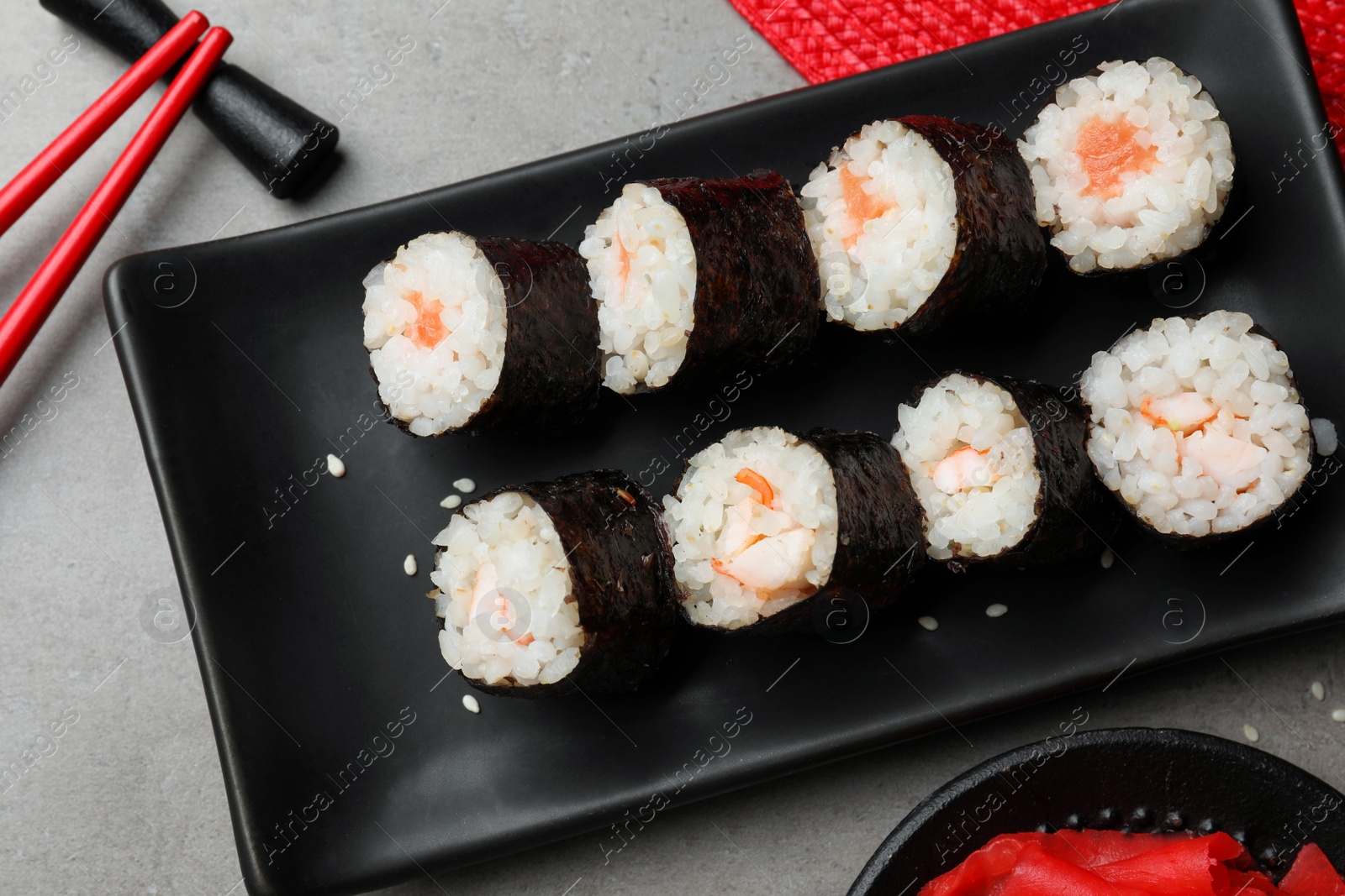 Photo of Tasty sushi rolls served on grey table, flat lay