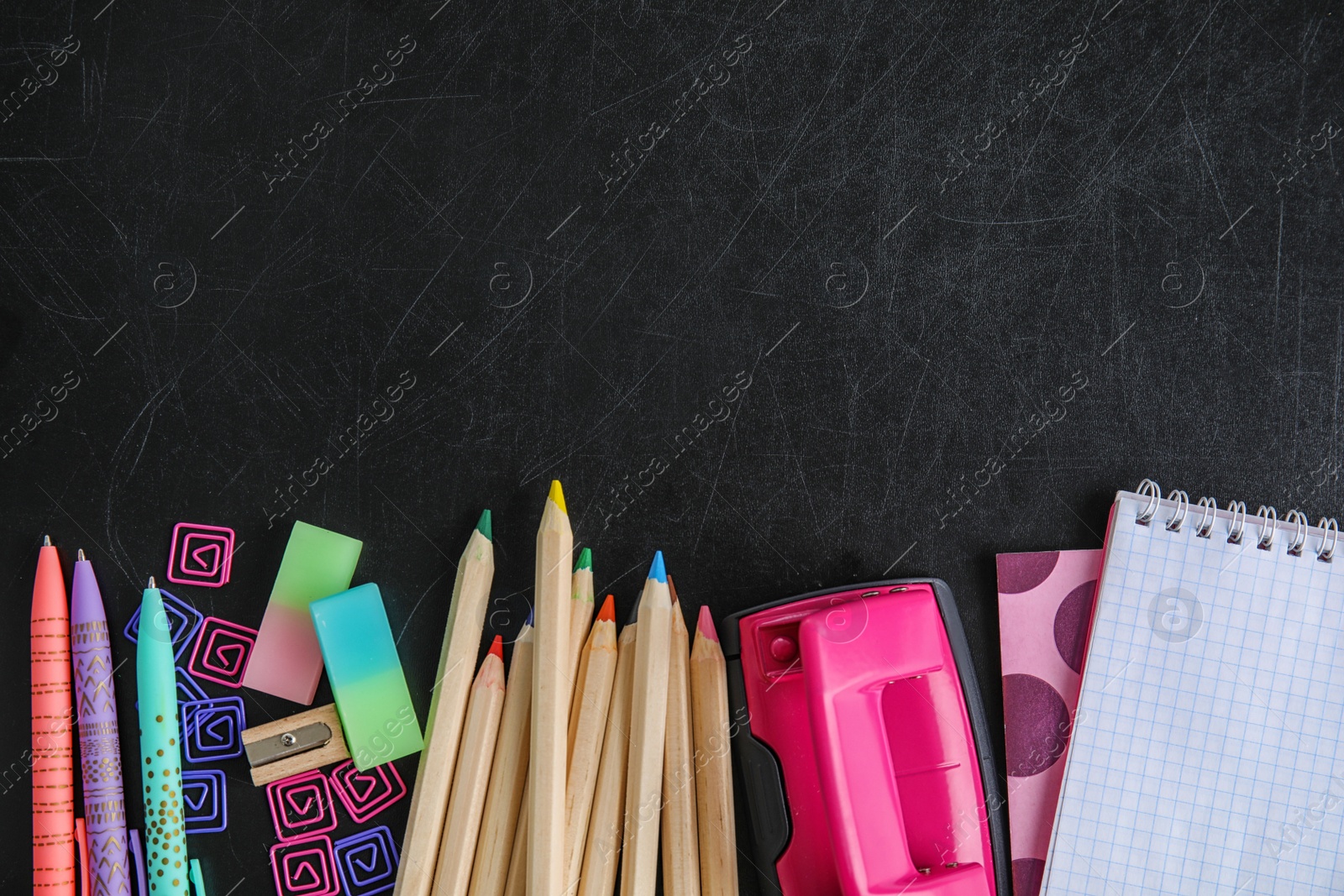 Photo of Flat lay composition with different school stationery on chalkboard surface