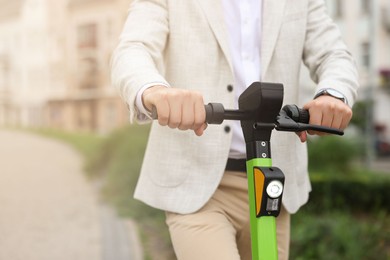 Photo of Businessman with modern kick scooter on city street, closeup. Space for text