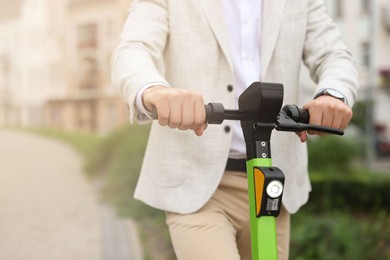 Businessman with modern kick scooter on city street, closeup. Space for text