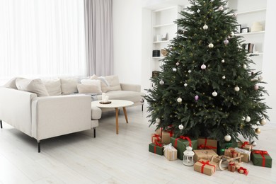 Beautifully wrapped gift boxes, wooden sleigh and lantern under Christmas tree in living room