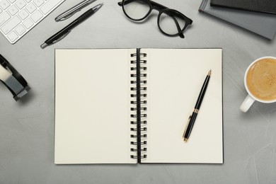 Photo of Open notebook, stationery, coffee and glasses on light grey table, flat lay