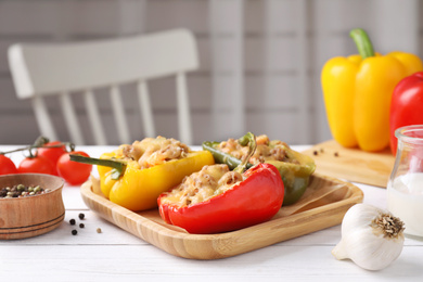 Photo of Tasty stuffed bell peppers served on white wooden table in kitchen