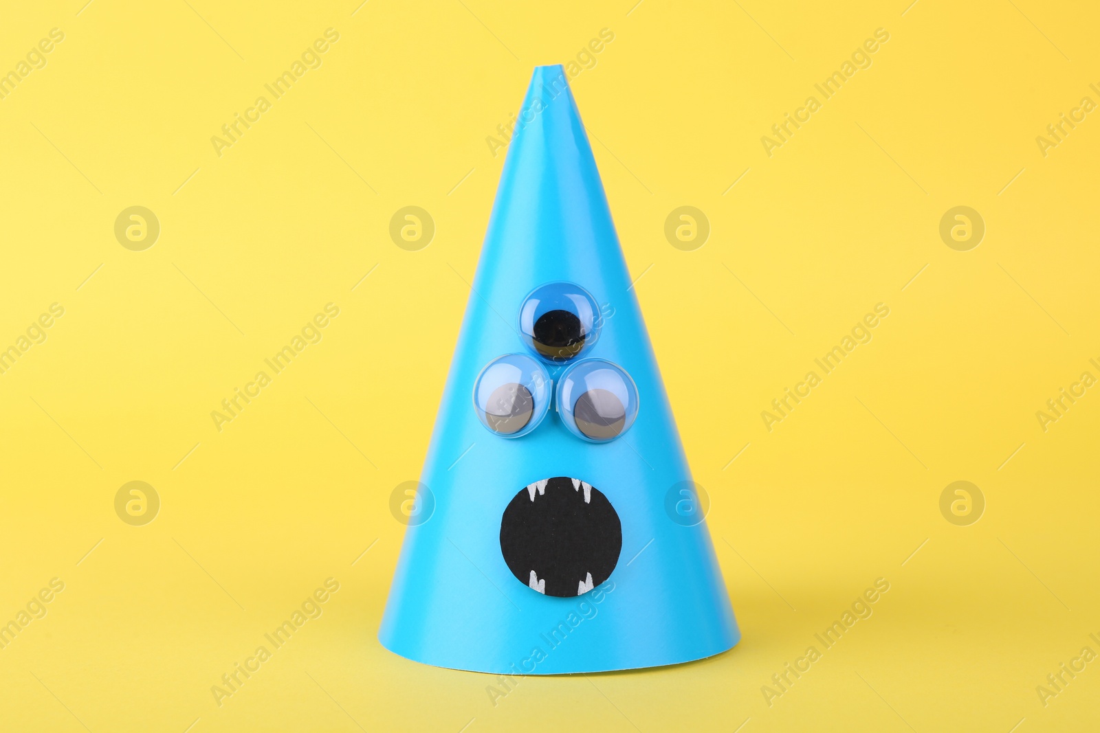 Photo of Spooky paper monster on yellow background. Halloween decoration