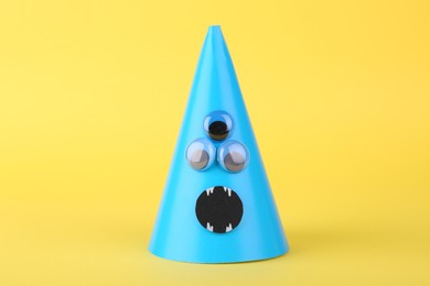 Photo of Spooky paper monster on yellow background. Halloween decoration