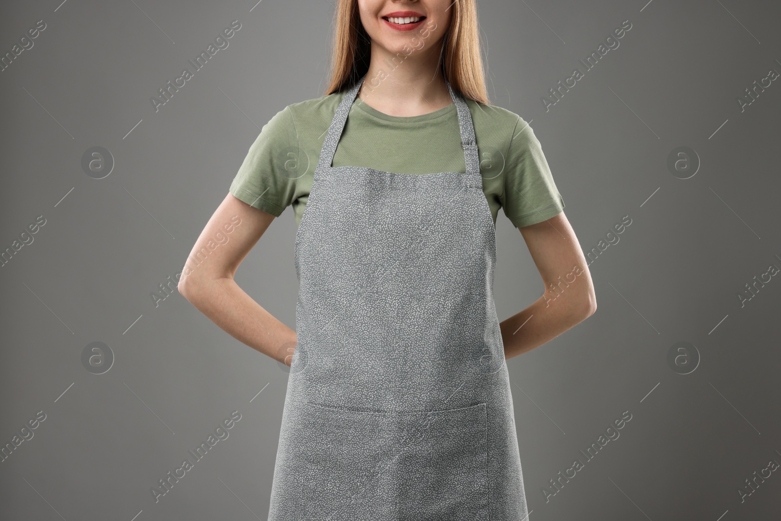 Photo of Woman wearing kitchen apron on grey background, closeup. Mockup for design