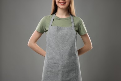 Woman wearing kitchen apron on grey background, closeup. Mockup for design
