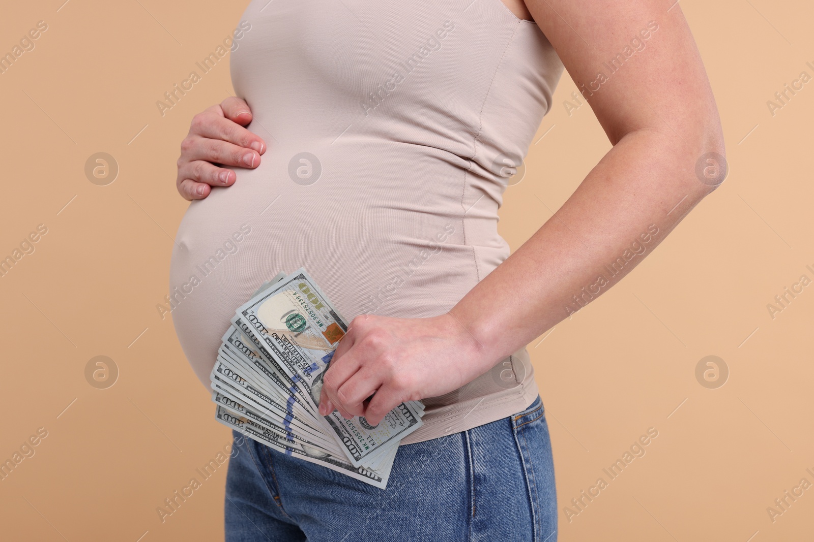 Photo of Surrogate mother. Pregnant woman with dollar banknotes on beige background, closeup