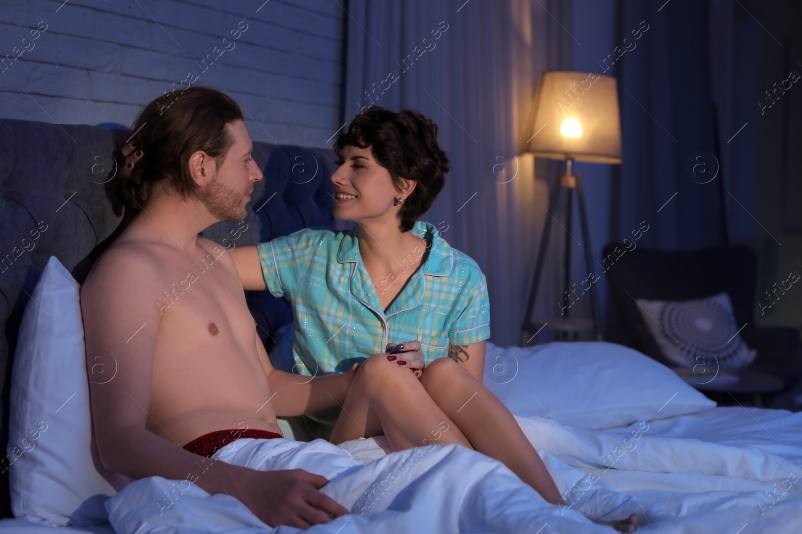 Photo of Young couple in love on bed at night time