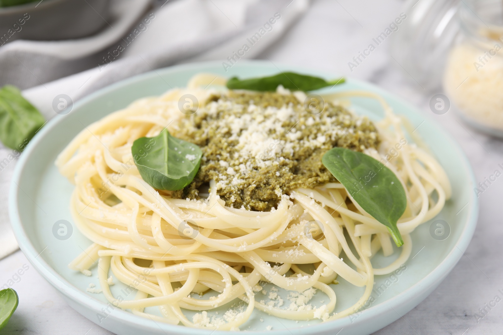 Photo of Tasty pasta with spinach, cheese and sauce on white marble table, closeup