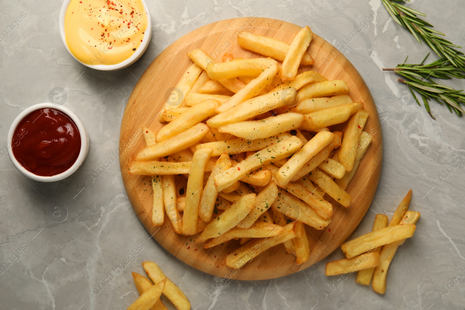 Photo of Delicious french fries served with sauces on grey marble table, flat lay