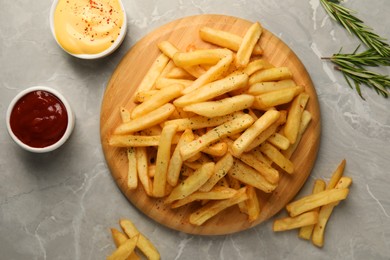 Delicious french fries served with sauces on grey marble table, flat lay