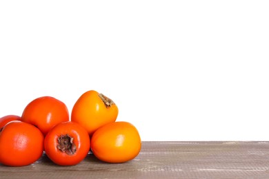 Delicious ripe juicy persimmons on wooden table against white background