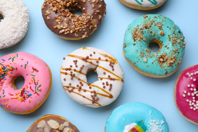Photo of Different tasty glazed donuts on light blue background, flat lay