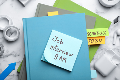 Photo of Reminder note about job interview and stationery on table, flat lay