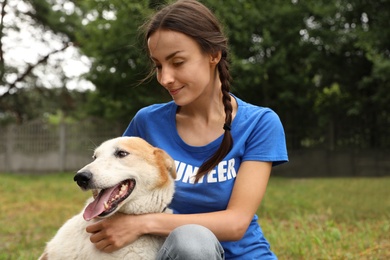 Female volunteer with homeless dog at animal shelter outdoors