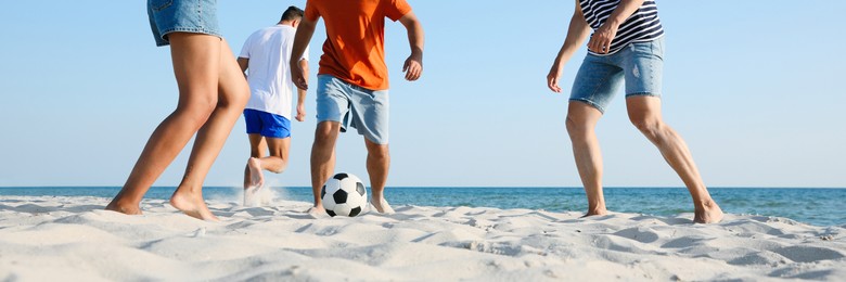 Group of friends playing football on sandy beach, low angle view. Banner design