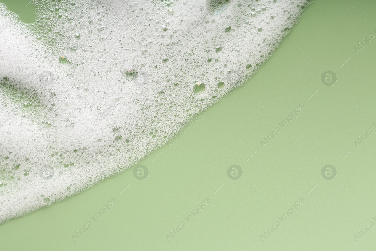 Photo of White fluffy foam on green background, top view. Space for text