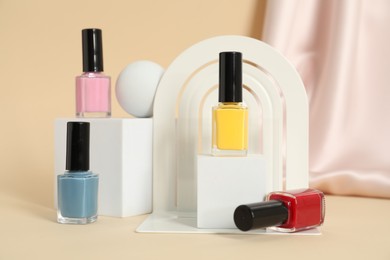 Photo of Stylish presentation of nail polishes on beige background