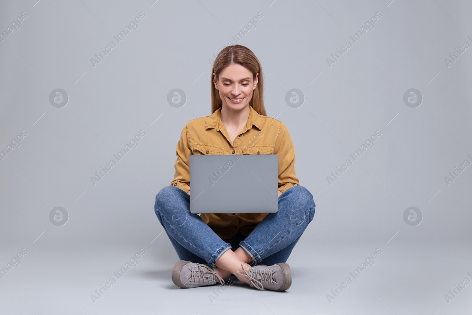 Photo of Happy woman with laptop on light grey background