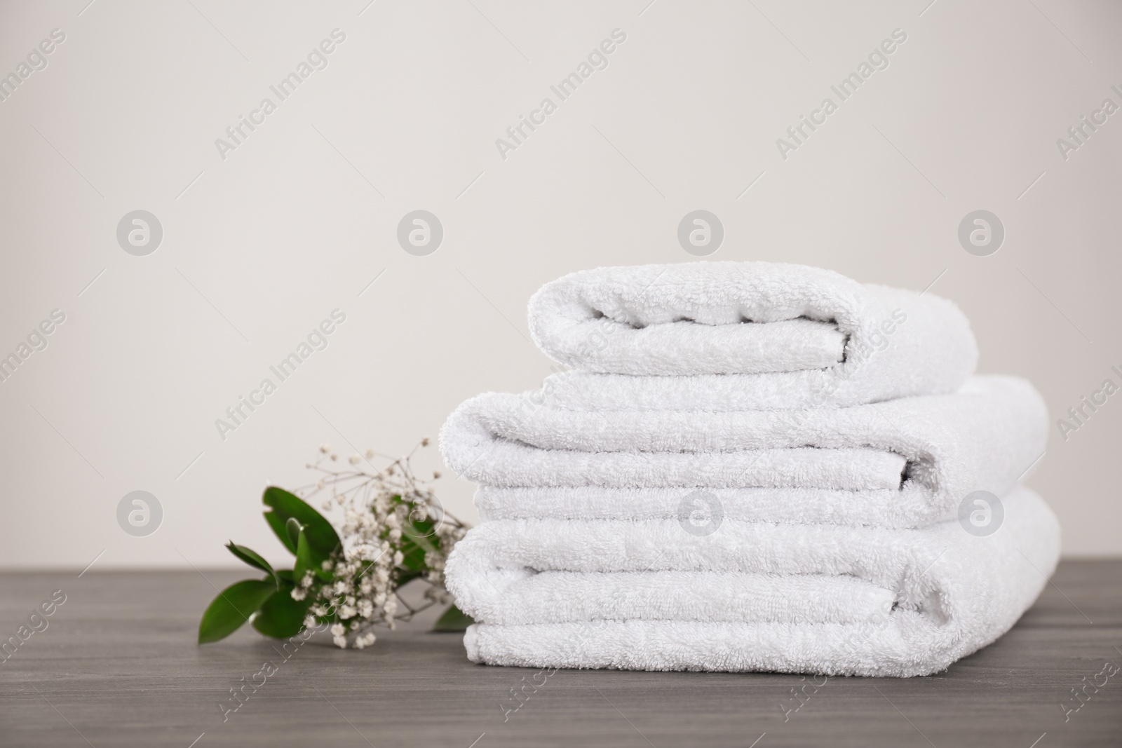 Photo of Fresh white towels and green plant on grey wooden table