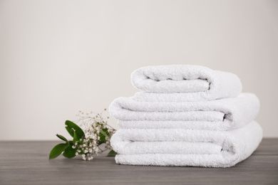 Fresh white towels and green plant on grey wooden table