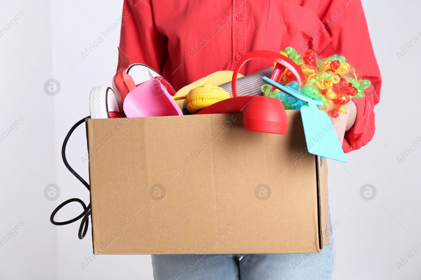 Photo of Woman holding box of unwanted stuff on white background, closeup