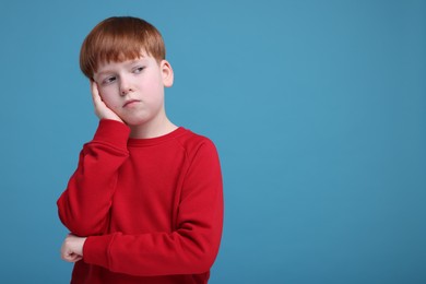 Photo of Portrait of sad little boy on light blue background, space for text