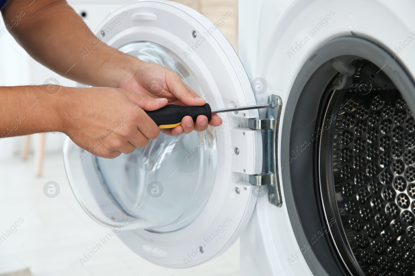 Photo of Young handyman fixing washing machine, closeup. Laundry day