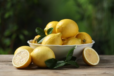 Photo of Fresh lemons and green leaves on wooden table