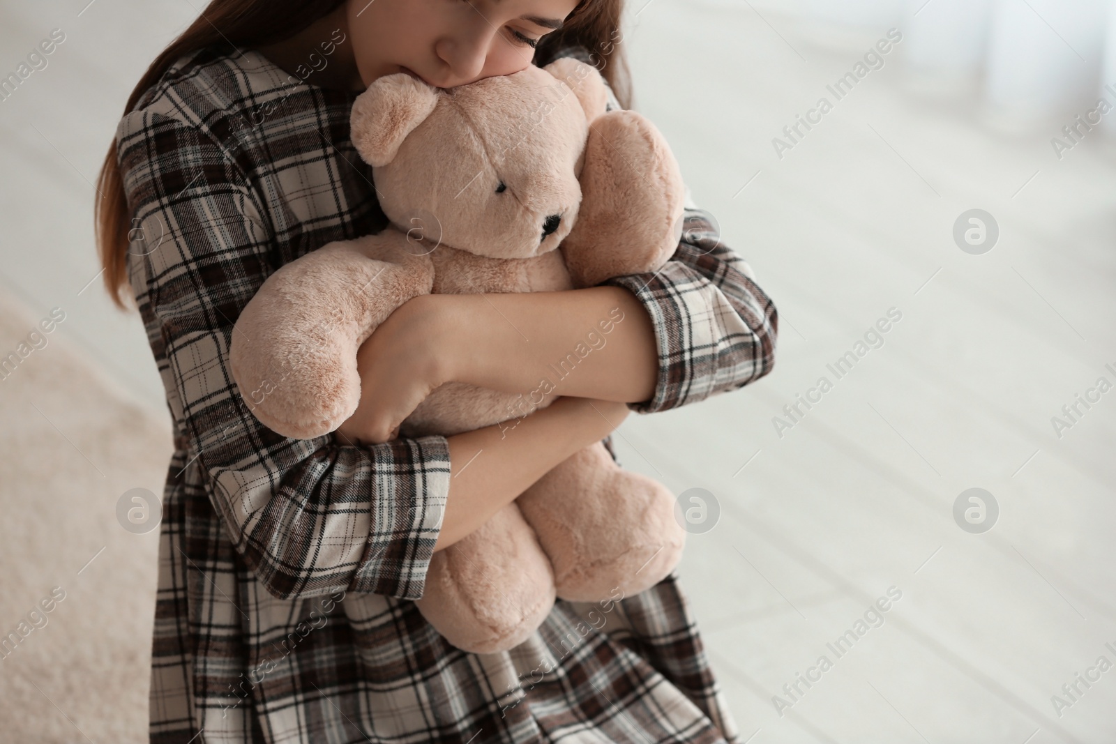 Photo of Upset girl with toy indoors, closeup. Space for text