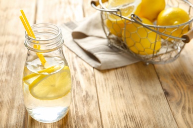 Photo of Bottle with lemon water on wooden table
