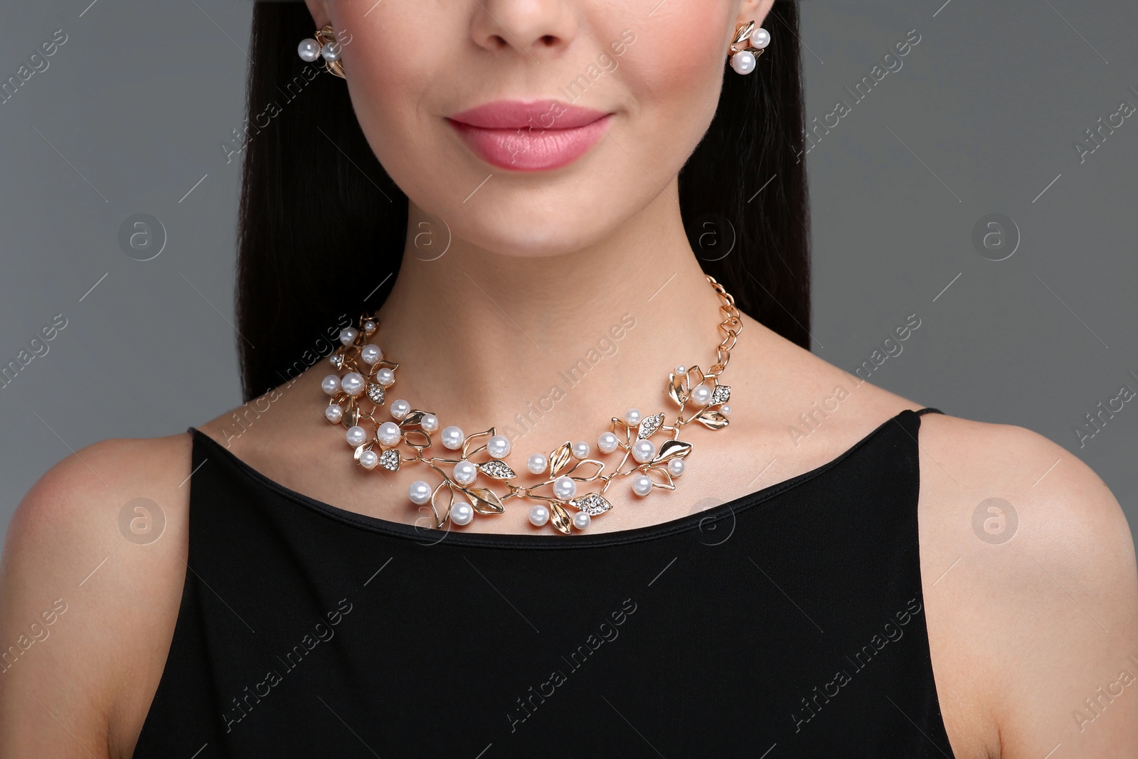 Photo of Young woman with elegant jewelry on dark grey background, closeup