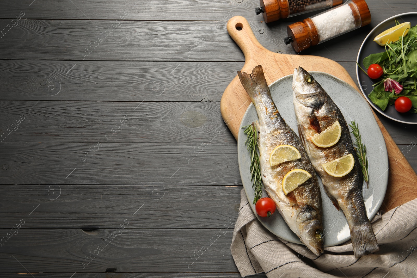 Photo of Delicious baked fish served on grey wooden table, top view. Space for text