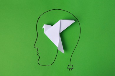 Drawn human head with white paper bird as solution idea on green background, top view