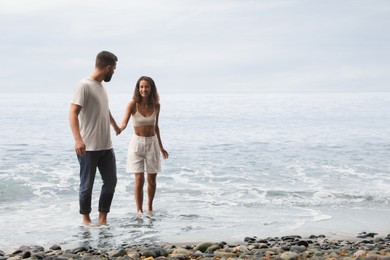 Happy young couple on beach near sea. Space for text