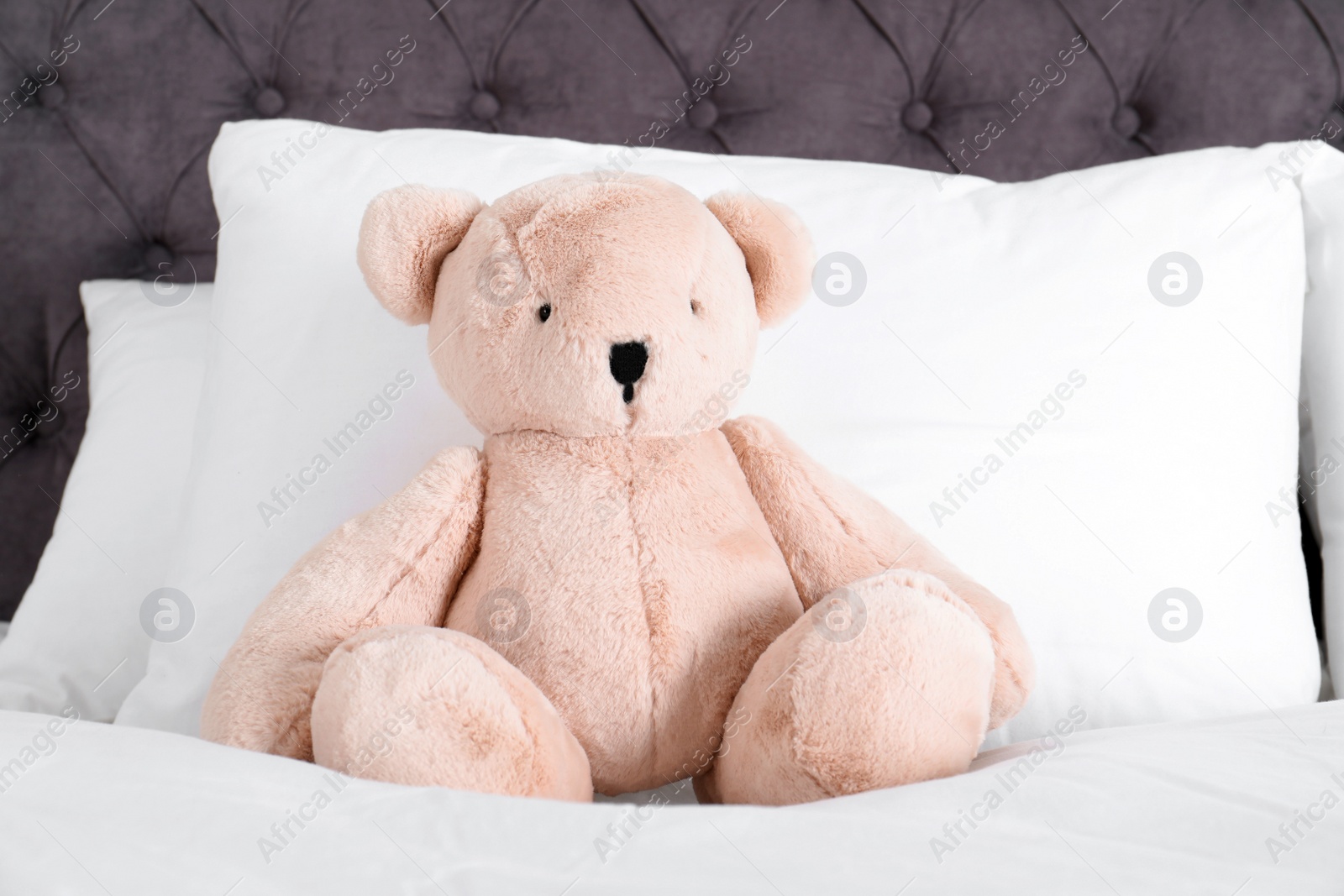 Photo of Cute teddy bear sitting on bed indoors