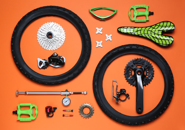 Photo of Set of different bicycle tools and parts on orange background, flat lay