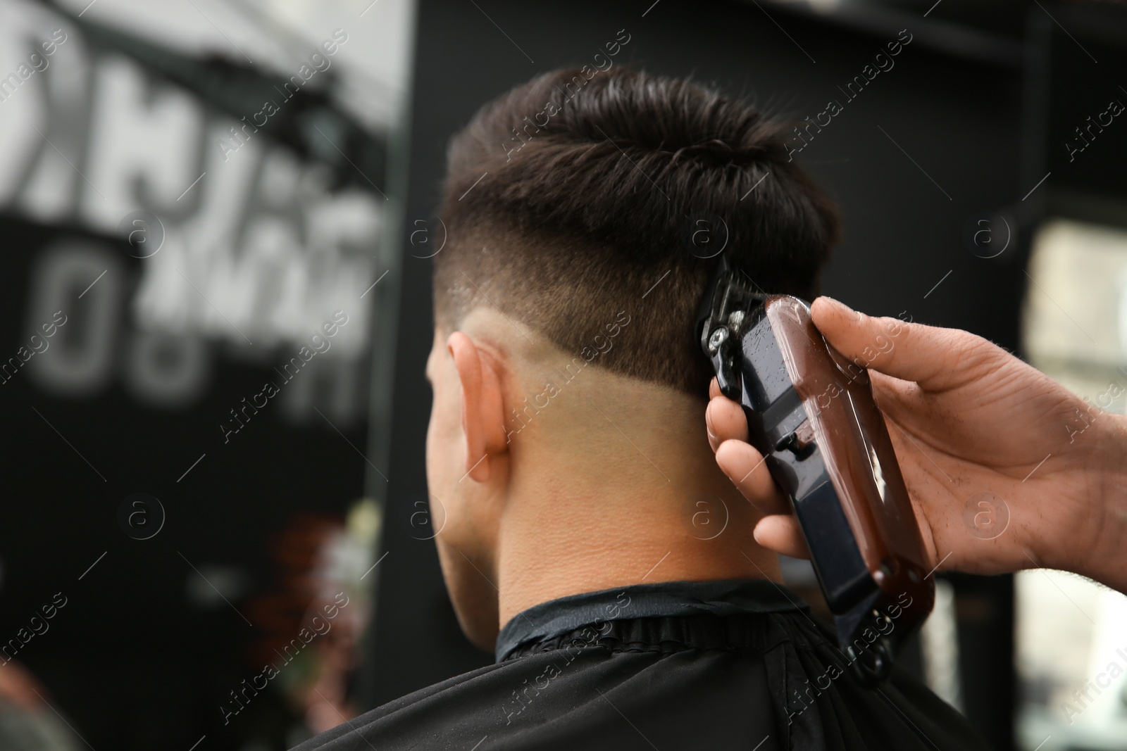 Photo of Professional barber making stylish haircut in salon, closeup