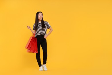 Photo of Smiling woman with shopping bags on yellow background. Space for text